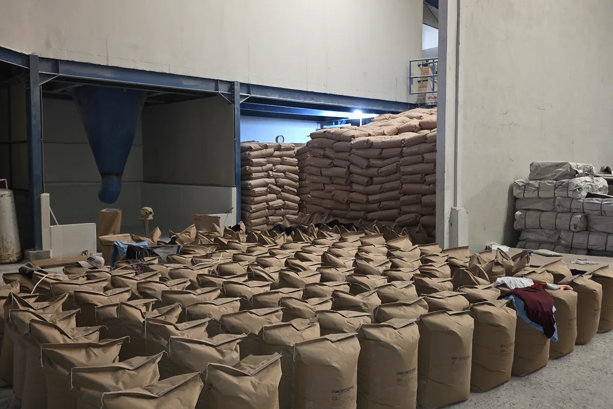 Karung bahan industri terbuka yang tersusun di dekat peralatan penanganan gudang